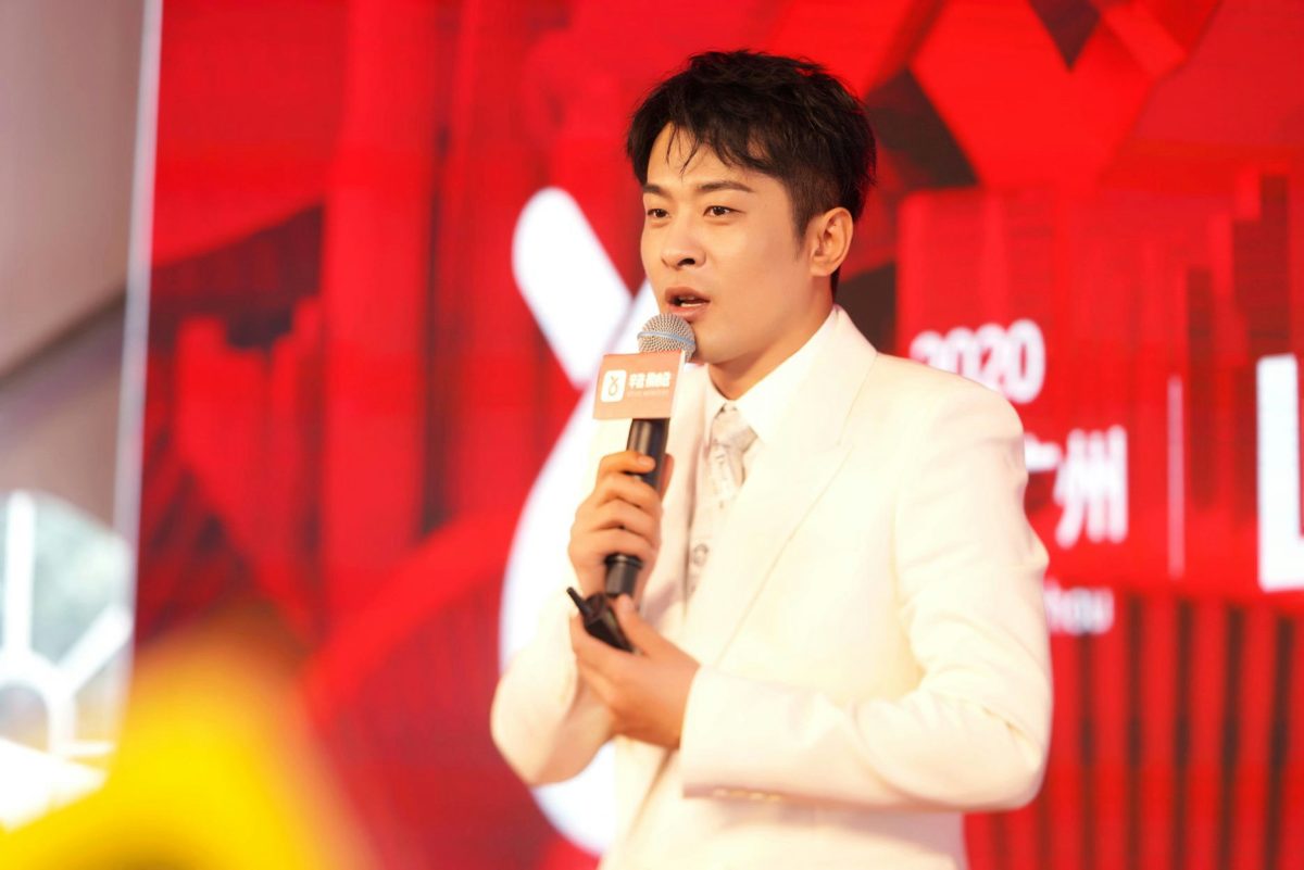 Xinba retirement Cotton Code scandalperson' 'microphone' 'white' 'suit' 'red' 'backdrop' 'speaking.