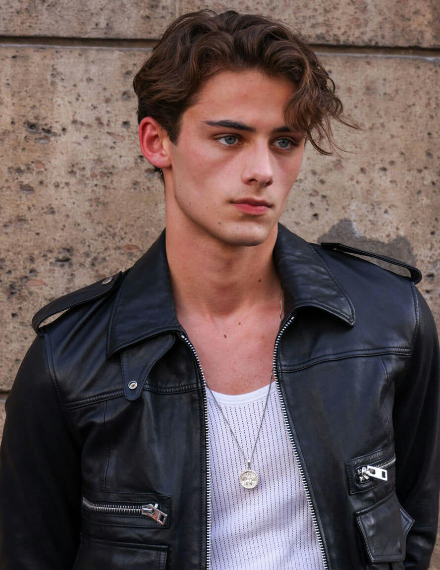 people-young man-A-blue eyes-A-brown wavy hair-A-black leather jacket-A-white ribbed tank top-A-silver pendant necklace