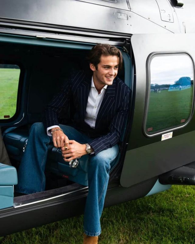 person-A-smiling-A-sitting in helicopter-A-pinstripe blazer-A-blue jeans-A-outdoor setting