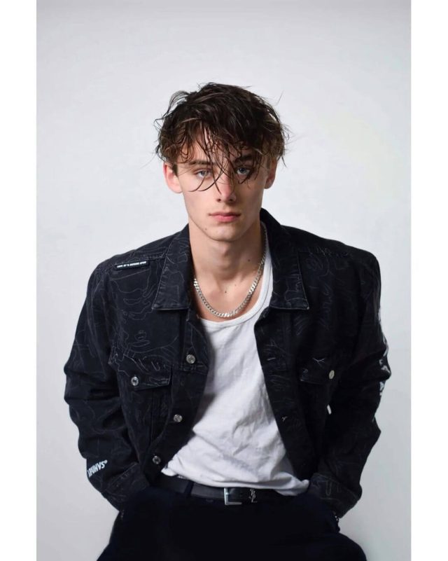 people-Young man-A-Blue eyes-A-Dark messy hair-A-Black patterned denim jacket-A-White tank top