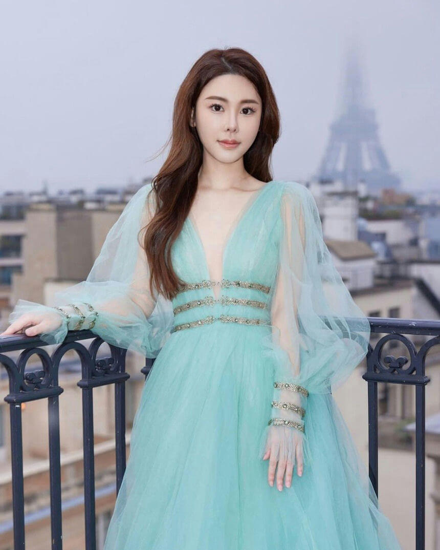 people-A-woman in a gown-A-Eiffel Tower in background-A-outdoor balcony setting-A-long flowing sleeves