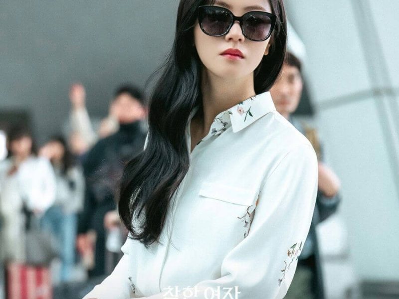 people-woman-A-sunglasses-A-white floral shirt-A-black wavy hair-A-airport crowd
