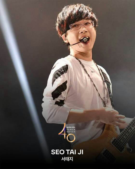 people-Seo Taiji-performing on stage-wearing glasses-holding a guitar-wearing a headset microphone