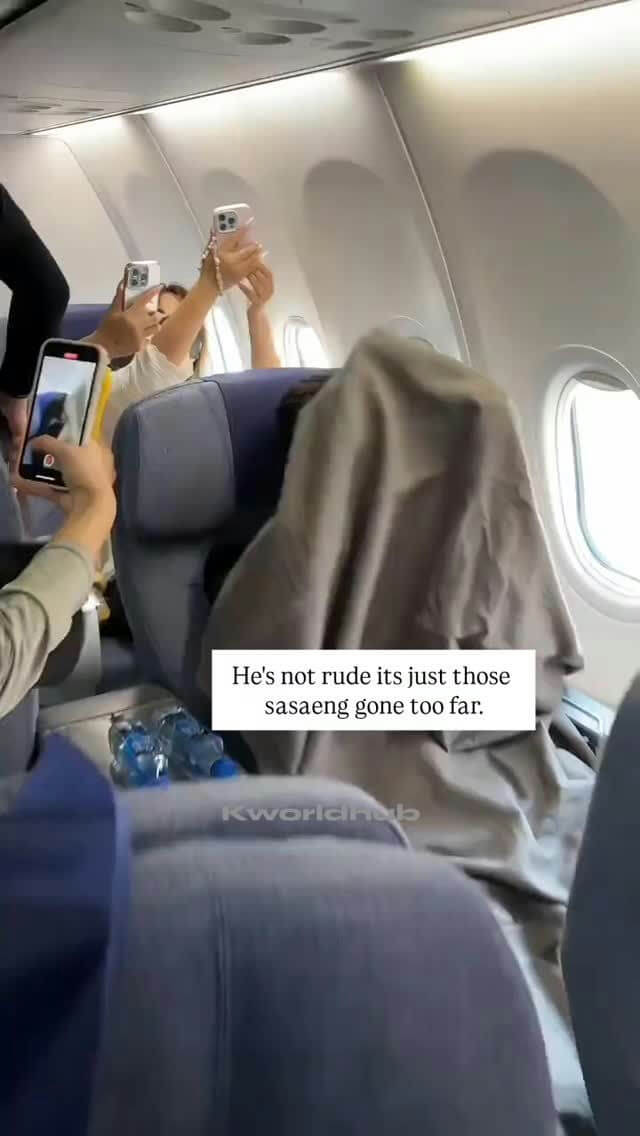 people-Multiple people taking photos-A-Airplane interior-B-Person covered with a blanket-C-Text overlay (