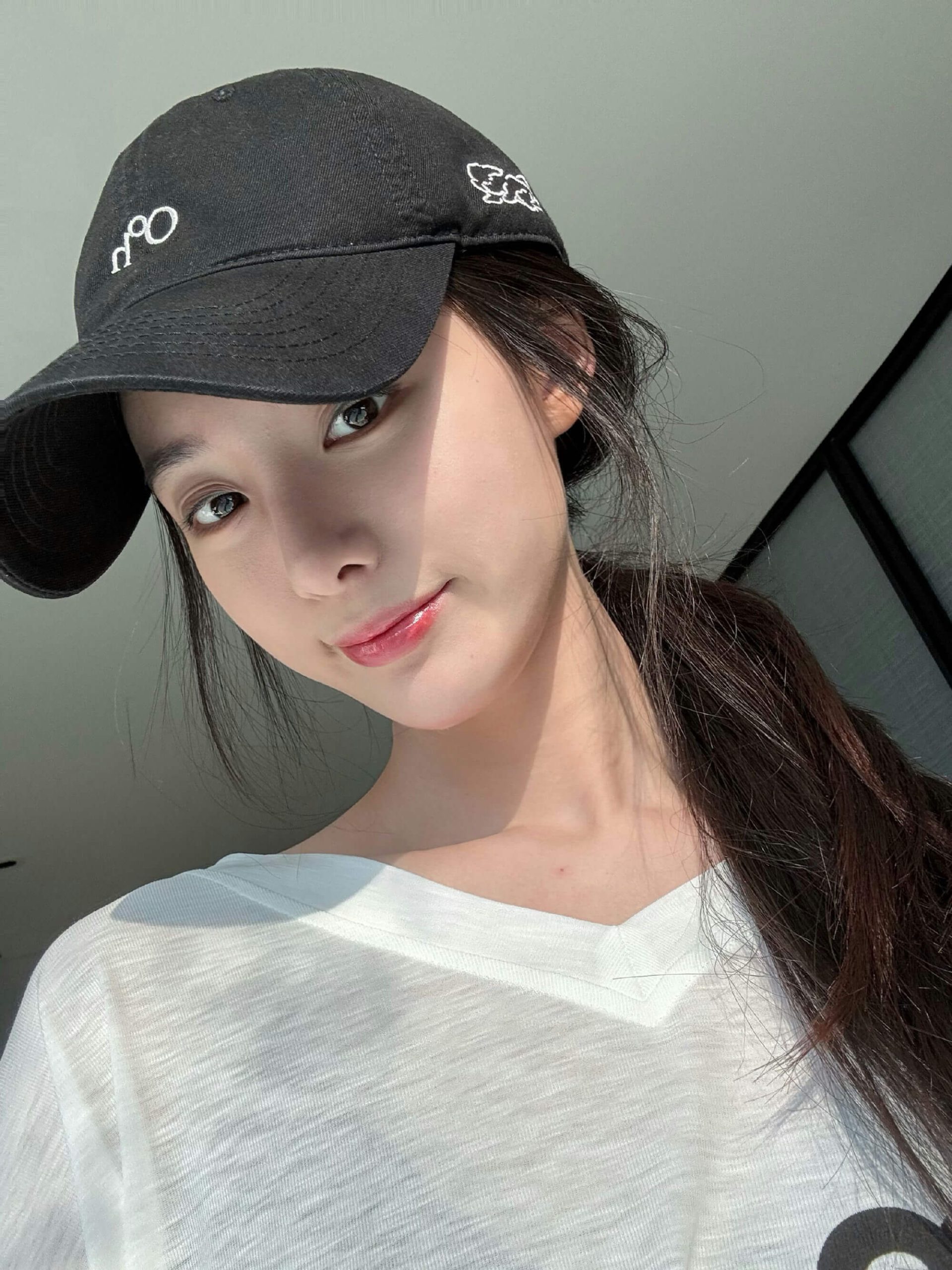 people-woman-A-selfie-A-black cap-A-white shirt-A-ponytail-A-sunlight