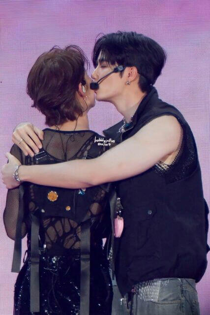 people-two males-kissing-on stage-wearing black outfits