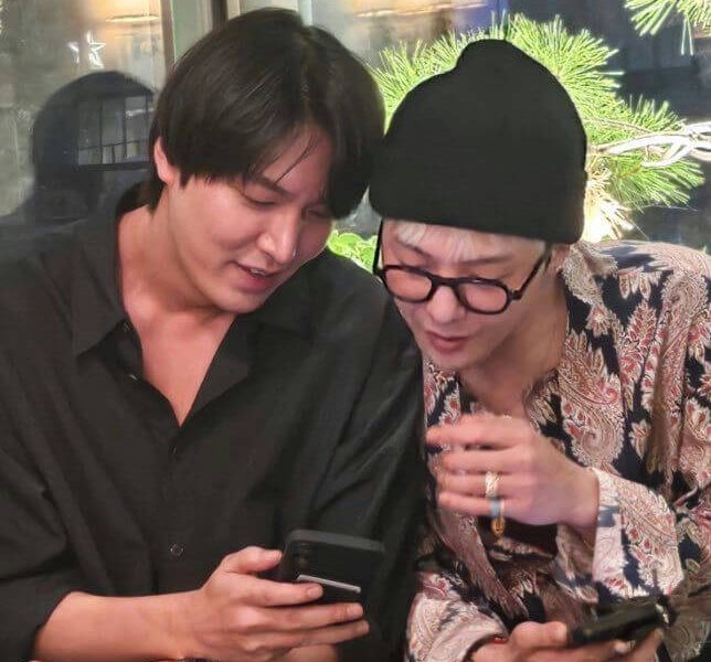people-Two men-A-looking at phone-B-sitting close together-C-wearing casual attire