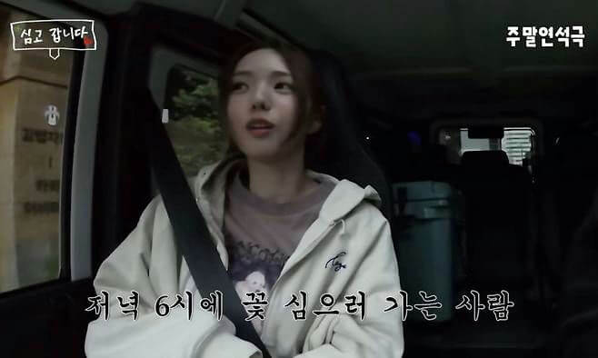 people-1-woman in a car-A-wearing a light-colored hooded jacket-B-with Korean subtitles visible-C-in a dark environment