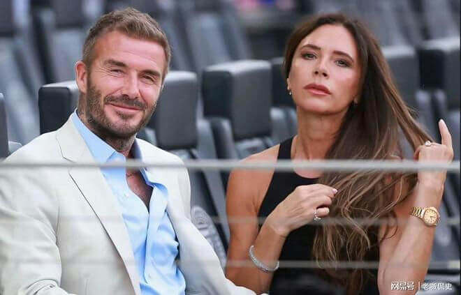 people-David Beckham-smiling-Victoria Beckham-serious expression-seated-outdoor event