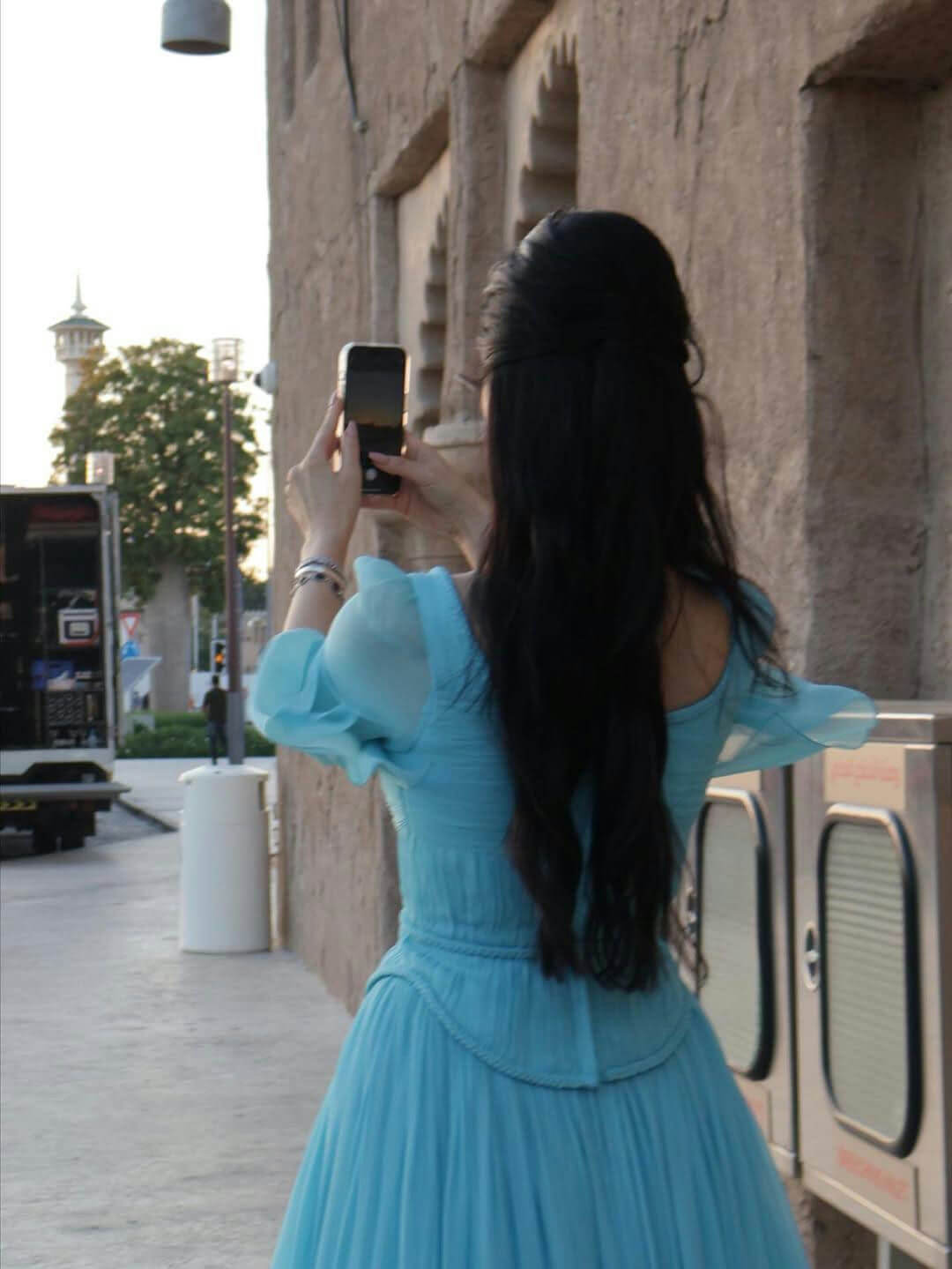 people-A-woman-A-taking-photo-A-blue-dress-B-long-black-hair-B-outdoor-C-historic-architecture-C