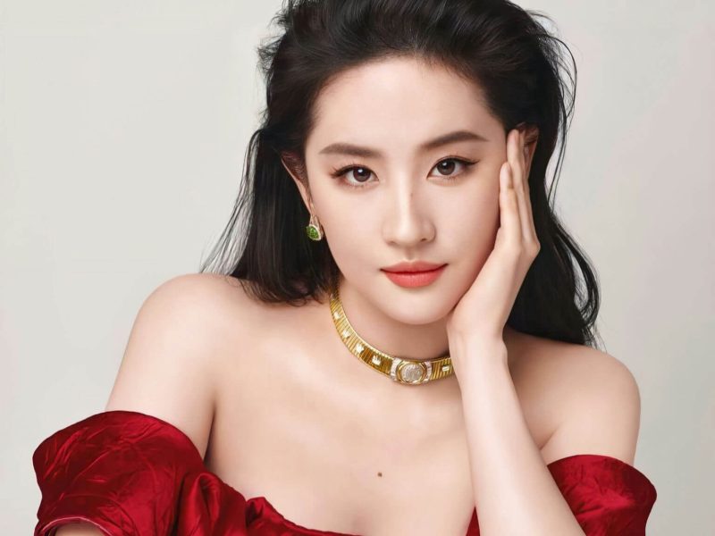 people-woman-A-red dress-A-gold jewelry-A-off-the-shoulder-A-dark hair-A-hand on face