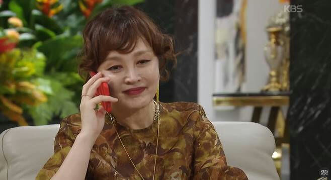 people-woman-A-on phone-B-smiling slightly-C-wearing patterned brown top