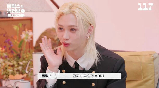 people-Felix (Stray Kids)-blond hair-wearing black jacket-raising hand-white shirt-interview setting