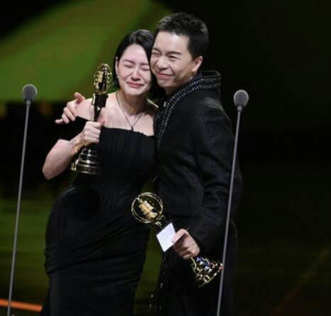people-woman-crying-A-man-hugging-A-holding-trophies-A-stage-A-black-dresses