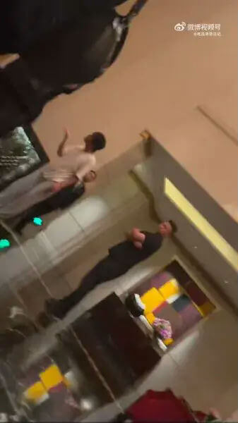 people-one man in white shirt-one man in black attire-one partially visible person-indoors-low light-sideways angle