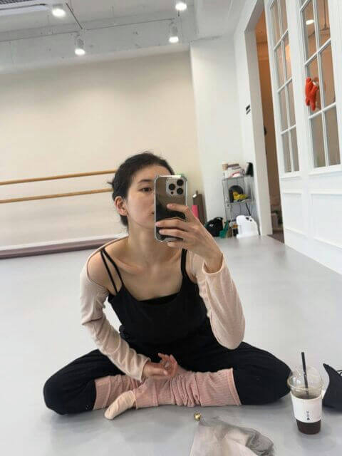 people-1-woman-A-sitting-on-floor-B-taking-mirror-selfie-C-in-dance-studio