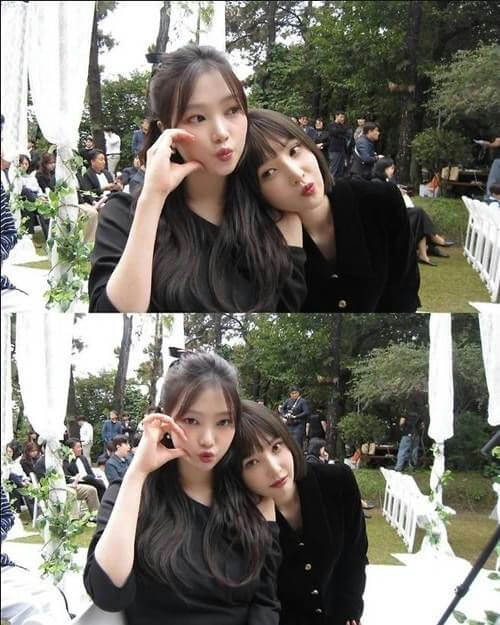 people-two young women-A-posing for a photo-A-outdoors at an event-A-wearing black clothing-B-one resting her head on the other's shoulder-B-making cute faces-C-outdoor setting with white decorations
