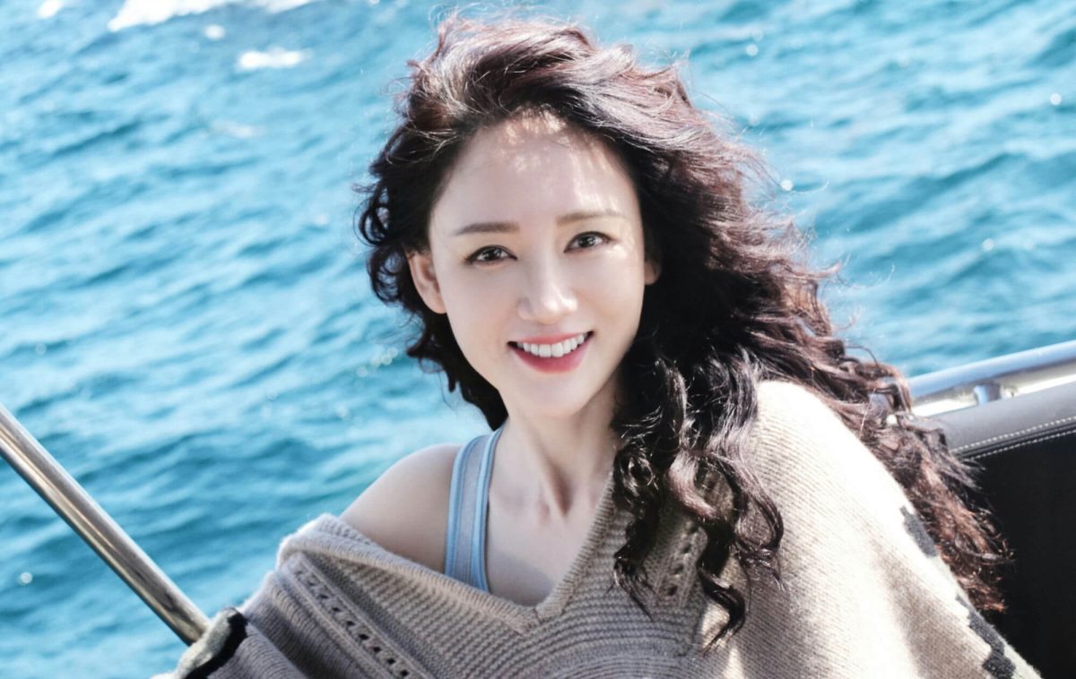 people-woman-A-smiling-A-dark curly hair-A-blue water background-A-boat railing