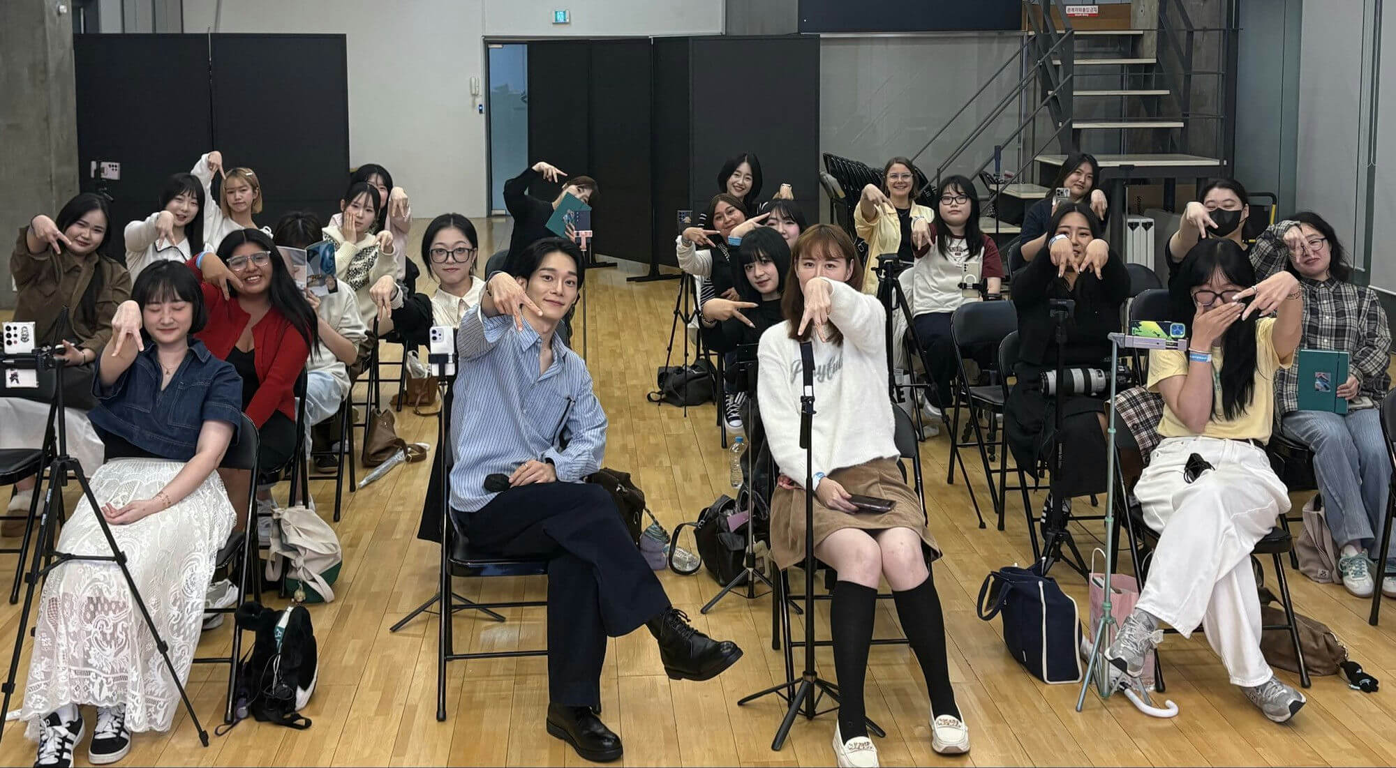 people-group-pointing-A-man-sitting-A-women-many-posing-B-indoor-A-casual-attire-B-chairs-A-tripods