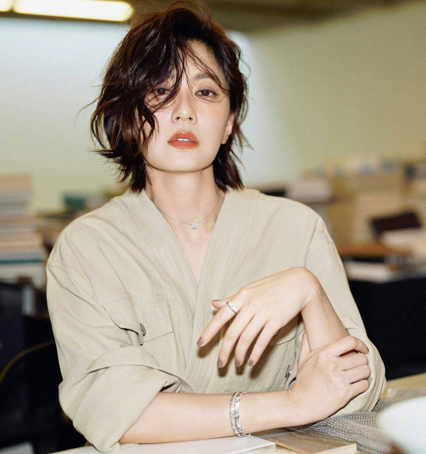 people-woman-A-short brown hair-A-khaki jacket-A-jewelry-A-seated indoors