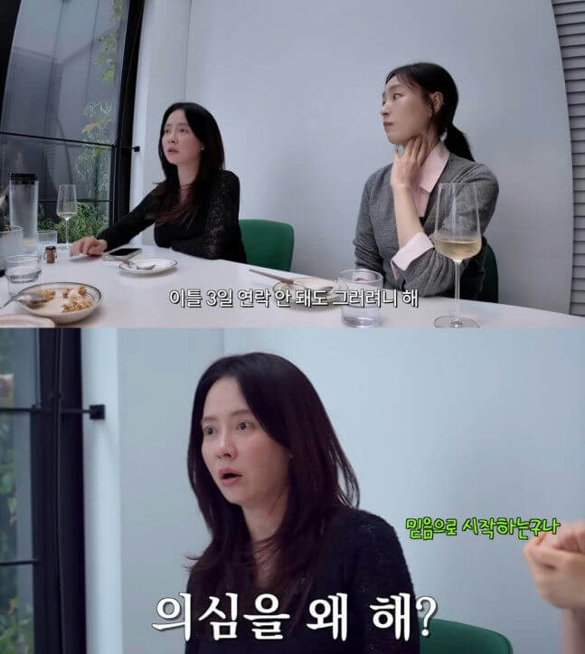 people-Two women sitting at a table indoors-Woman in black top looking surprised-Woman in gray cardigan looking thoughtful-Woman in black top asking a question-Woman in gray cardigan listening to conversation