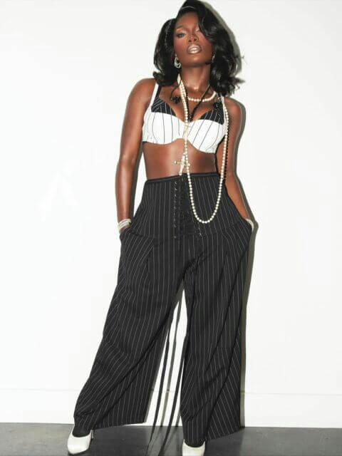 people-1-woman-A-dark skin-A-black hair-A-bra top-A-wide-leg pinstripe pants-A-pearl necklaces-A-cross necklace