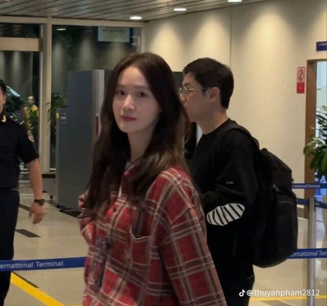 people-woman-plaid shirt-man-backpack-airport sign-red and black plaid shirt