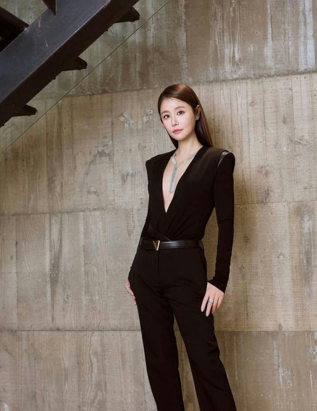 people-1-woman-A-black outfit-A-deep V-neckline-A-staircase background-A-diamond necklace