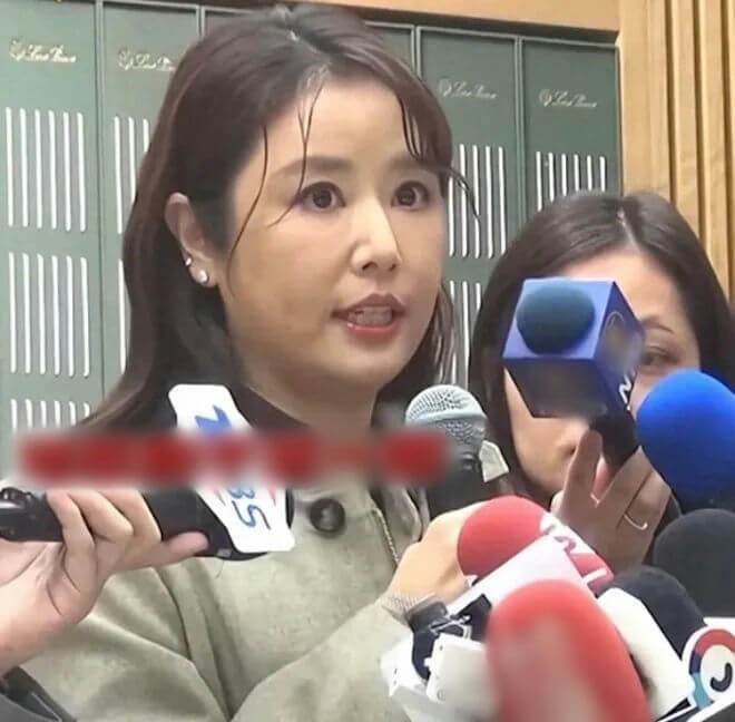 people-woman-speaking-to-press-A-microphones-A-earrings-B-blurry-red-bar-C