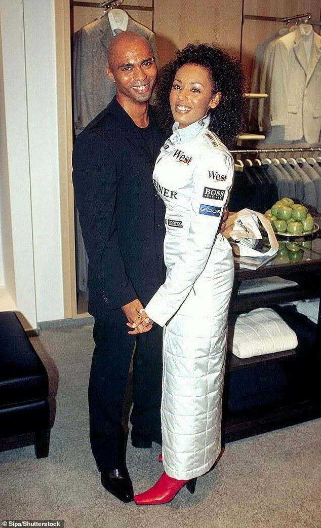 people-Melanie Brown (Mel B)-A-Jimmy Gulzar-B-smiling-C-holding hands-D-racing suit (white and sponsor logos)-E-red square-toed heels