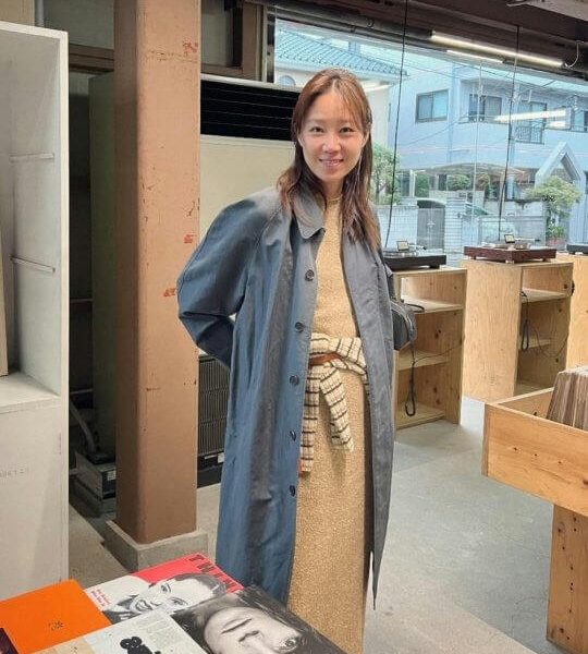 people-1-woman-A-smiling-A-long-blue-trench-coat-A-standing-indoors-A-in-a-store