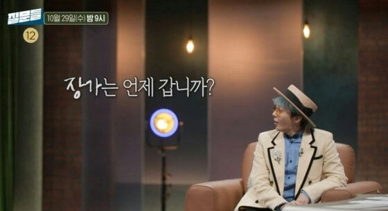people-one man-A-sitting-B-wearing a light-colored blazer and a straw hat-C-Korean text overlay asking a question