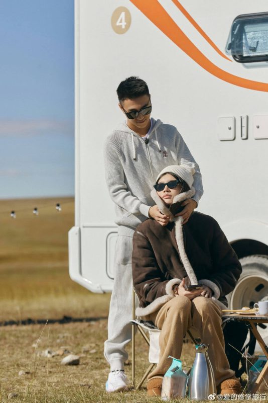 people-A-couple outdoors-B-man standing behind woman-C-RV in background