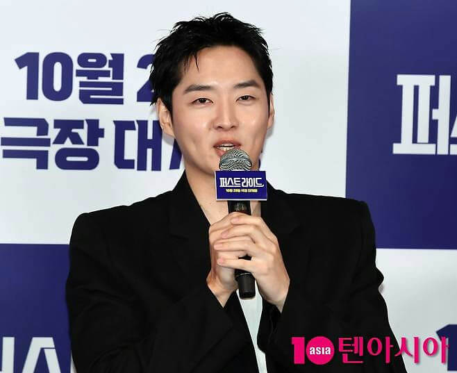 people-Man-A-Black Suit-A-Holding Microphone-A-Speaking-A-Korean Text Background