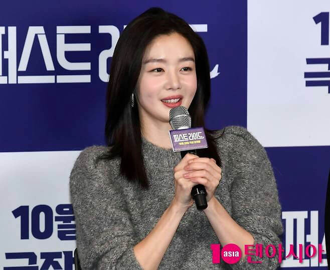 people-woman-Korean actress Go Ara-A-holding microphone-A-grey fuzzy sweater-A-smiling-A-event backdrop