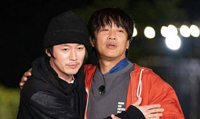 people-Two Asian men embracing-A-Black beanie-B-Orange jacket-C-Dark background lights
