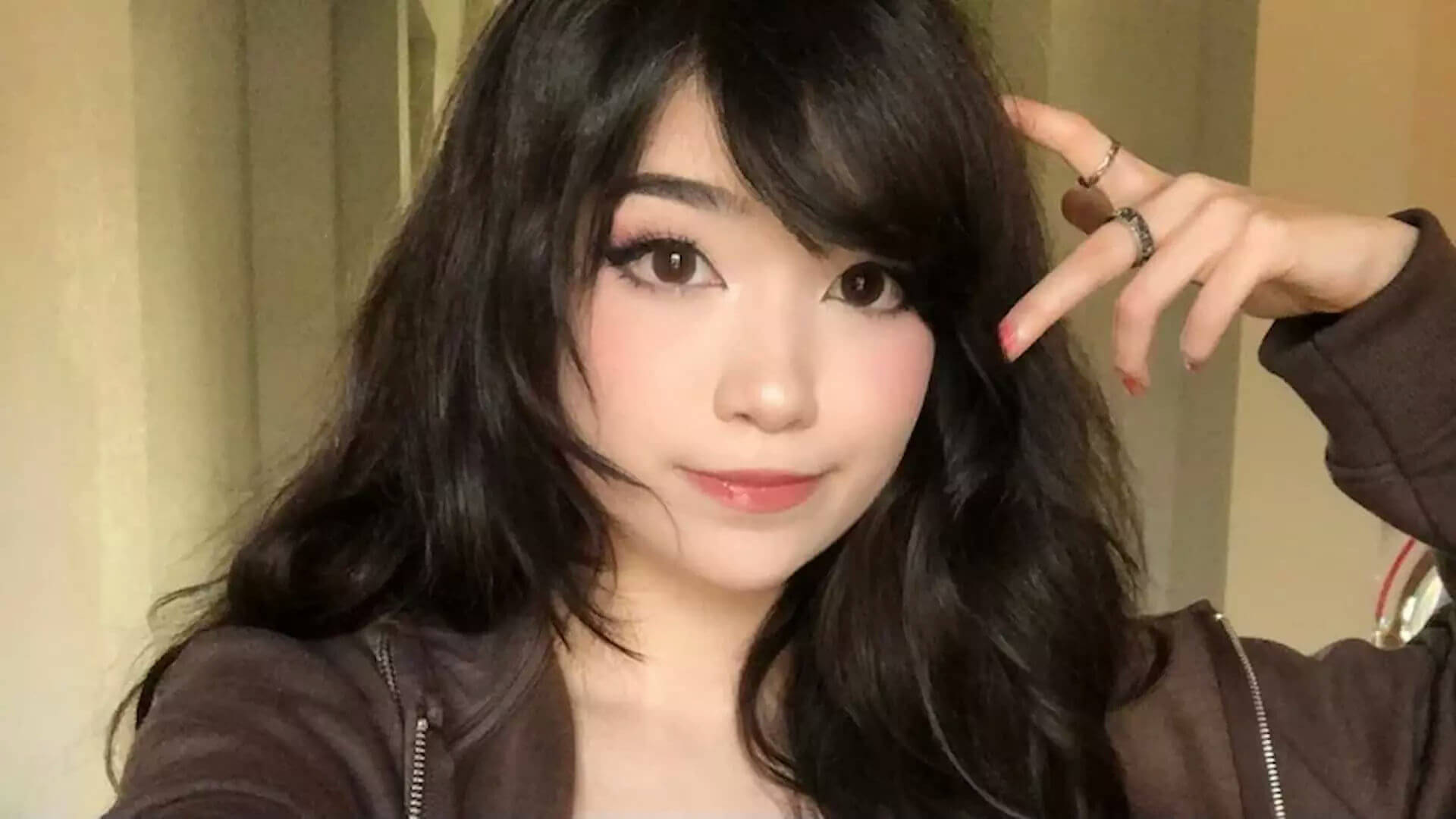 people-young woman-A-dark hair-A-brown jacket-B-rings on fingers-C-light makeup