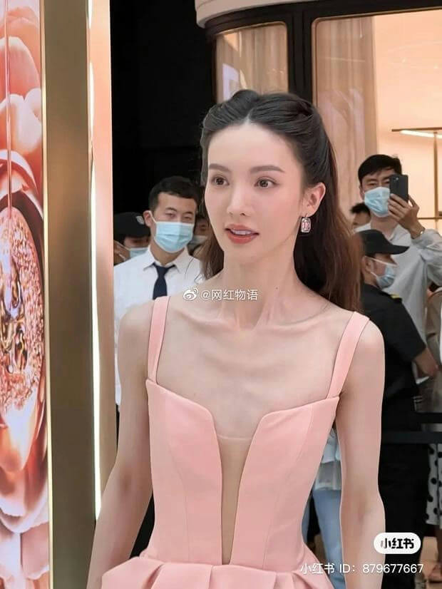 people-woman in pink dress-A-thin collarbones-B-crowd in background-C-social media watermark