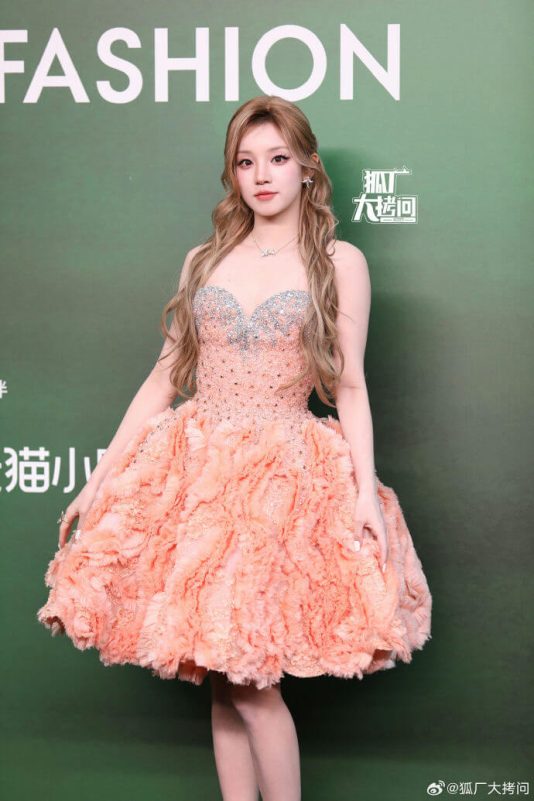 people-A-female celebrity-A-pink strapless dress-A-fluffy skirt-A-long wavy blonde hair-A-green backdrop