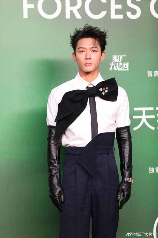 people-A-male celebrity-A-fashion-A-black bow tie-A-white shirt-A-long black gloves-A-navy high-waisted trousers