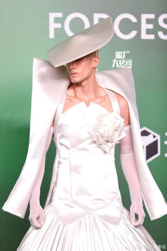 people-1-male model-A-white satin outfit-A-exaggerated shoulders-A-wide-brimmed hat-A-white rose accent-A-long white gloves