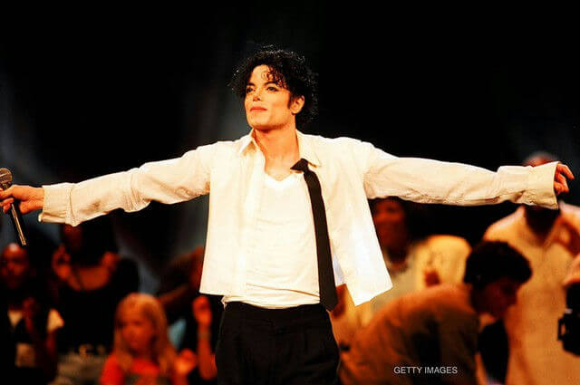 people-Michael Jackson-A-singer-A-performer-A-stage-B-arms outstretched-C-white shirt-C-black tie
