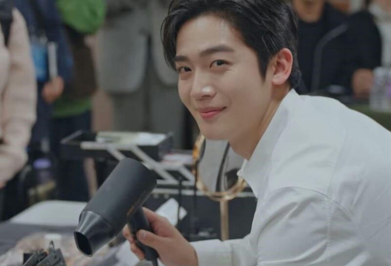 people-young Asian man-A-white collared shirt-B-holding black hairdryer-C-smiling and looking at camera