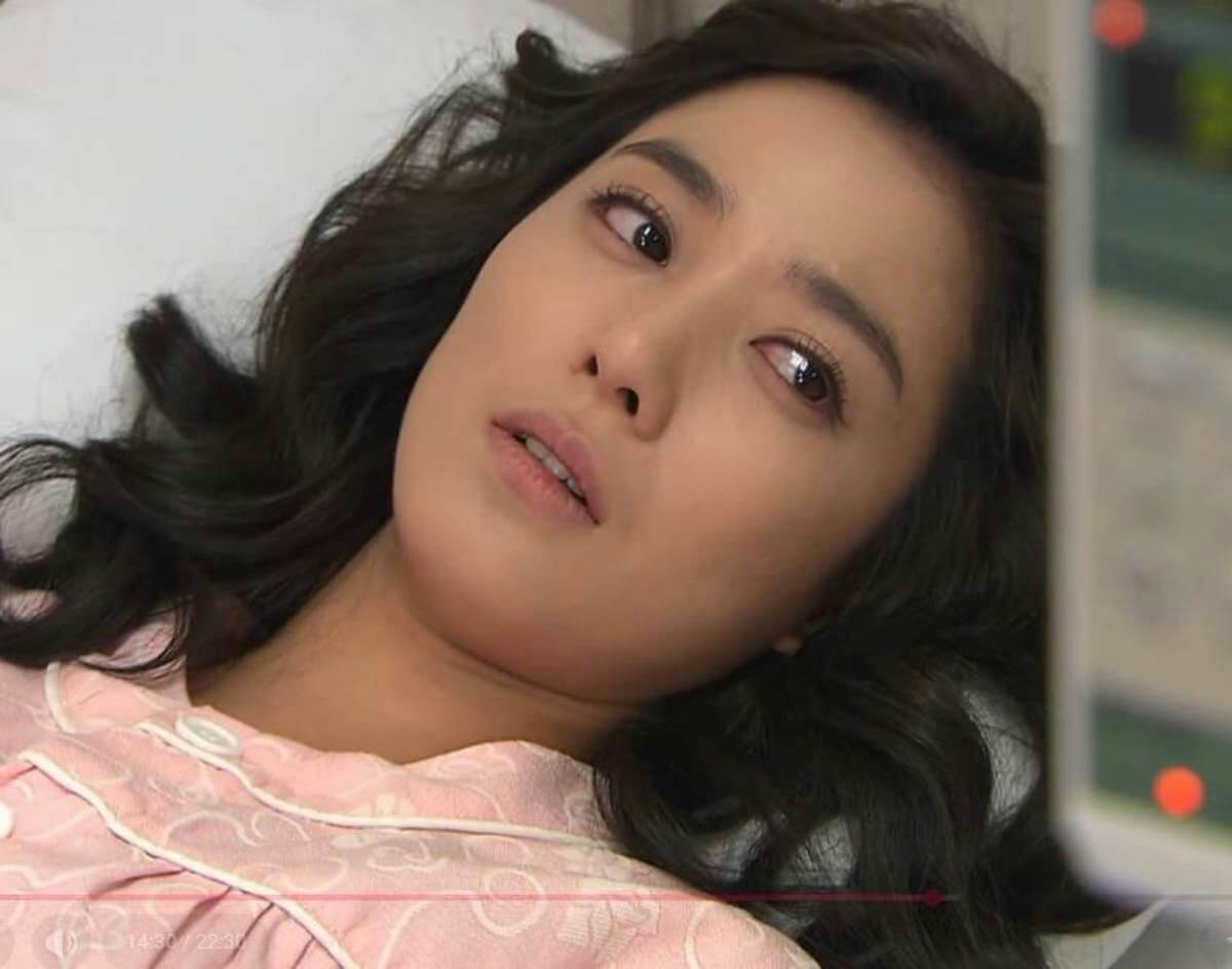 people-woman-lying down-pink pajamas-dark wavy hair-surprised expression-hospital setting