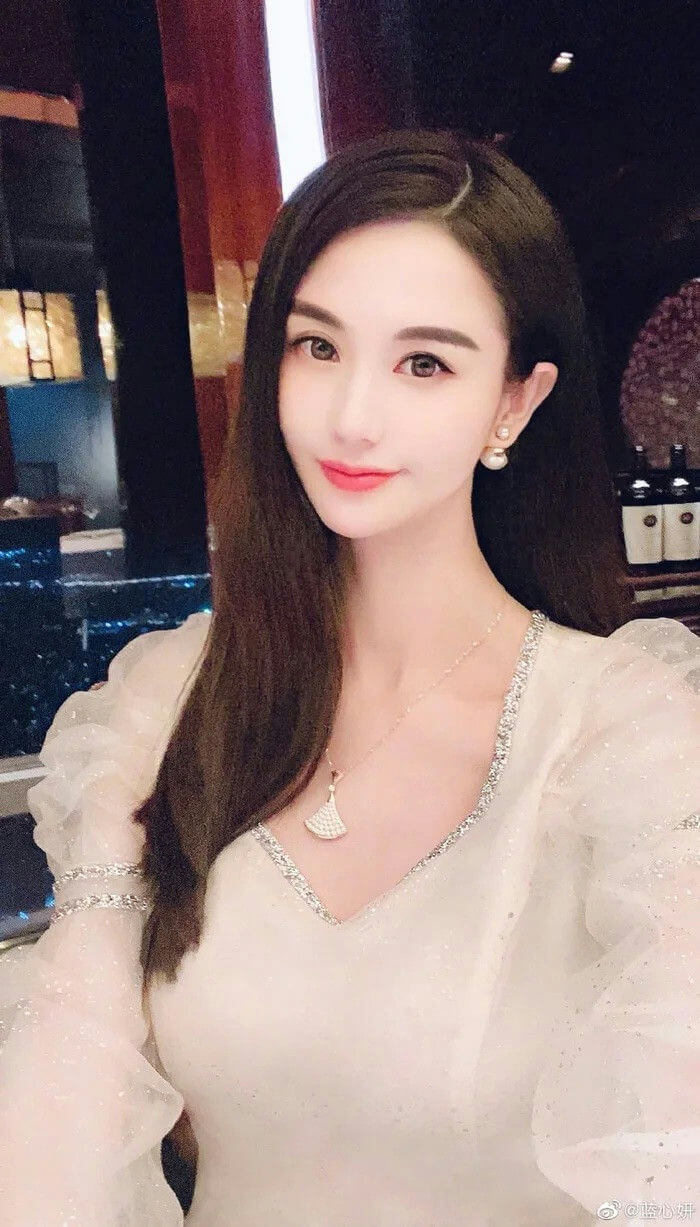 people-woman-A-long dark hair-A-white dress with sparkly trim-A-pearl earrings-A-pendant necklace