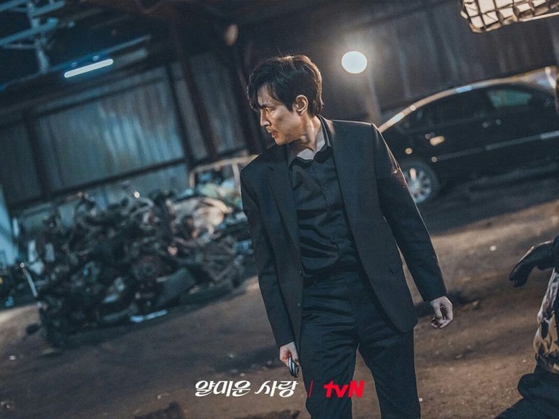 people-One man in a black suit-A-intense gaze-B-dark setting-C-trash pile