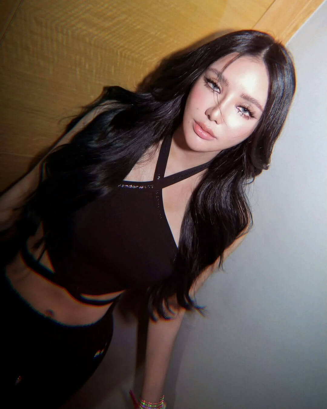 people-Woman-Black Top-Long Dark Hair-Heavy Makeup-Crop Top-Leaning Against Wall