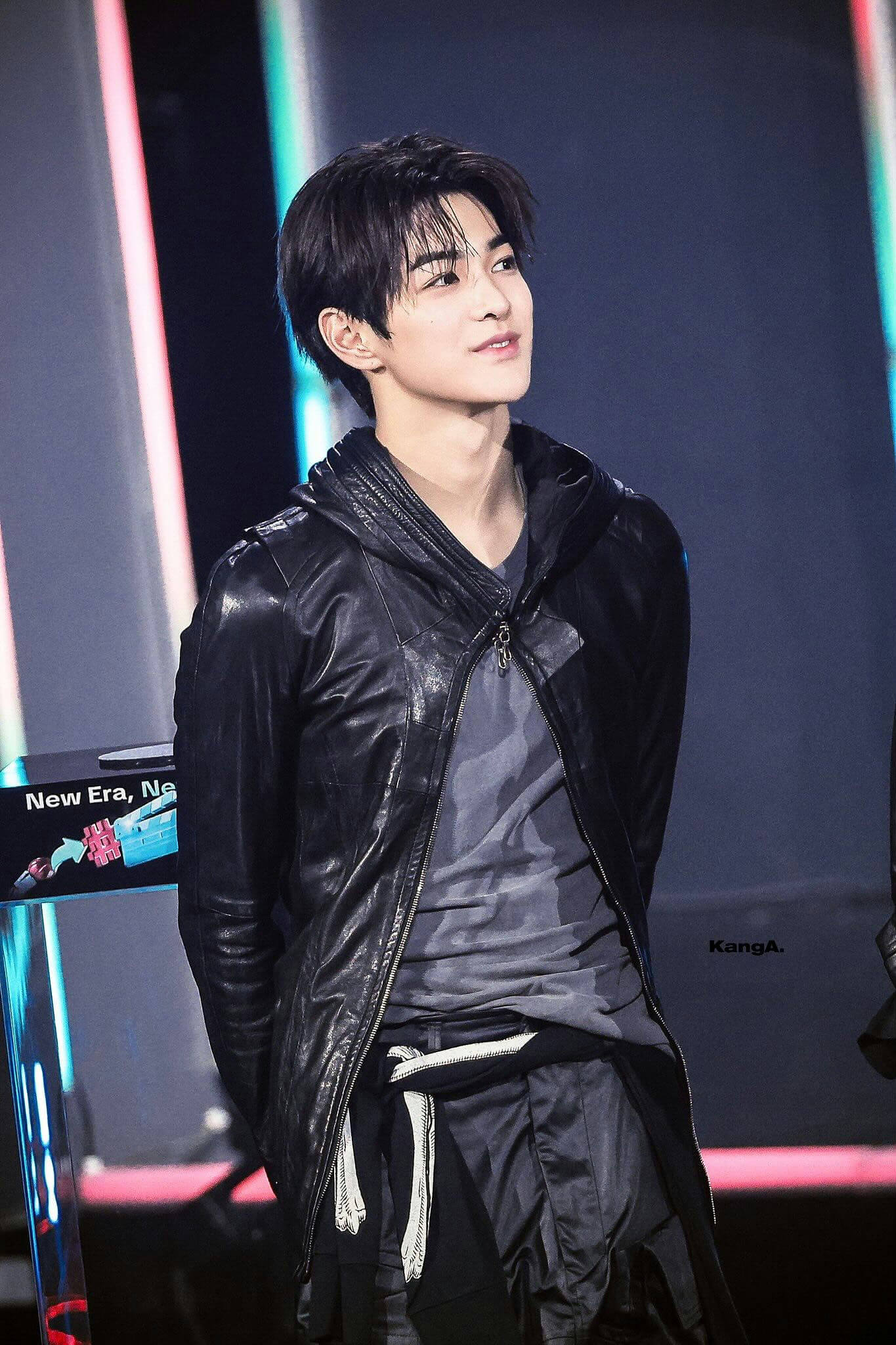 people-One young man-A-East Asian descent-A-dark hair-A-wearing black leather jacket-A-looking up and to the right-A-on stage or set-A-stage lighting present