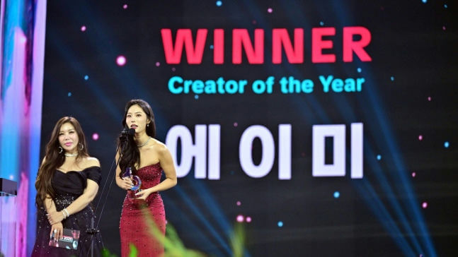 people-Two women on stage-A-receiving award-B-presenting award-C-Backdrop with text