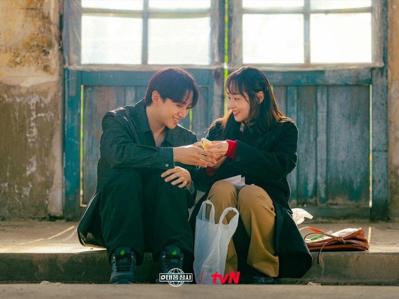 people-two young adults-A-sharing food-A-smiling-A-sitting outdoors-B-Korean drama promotional image-C-worn background-C